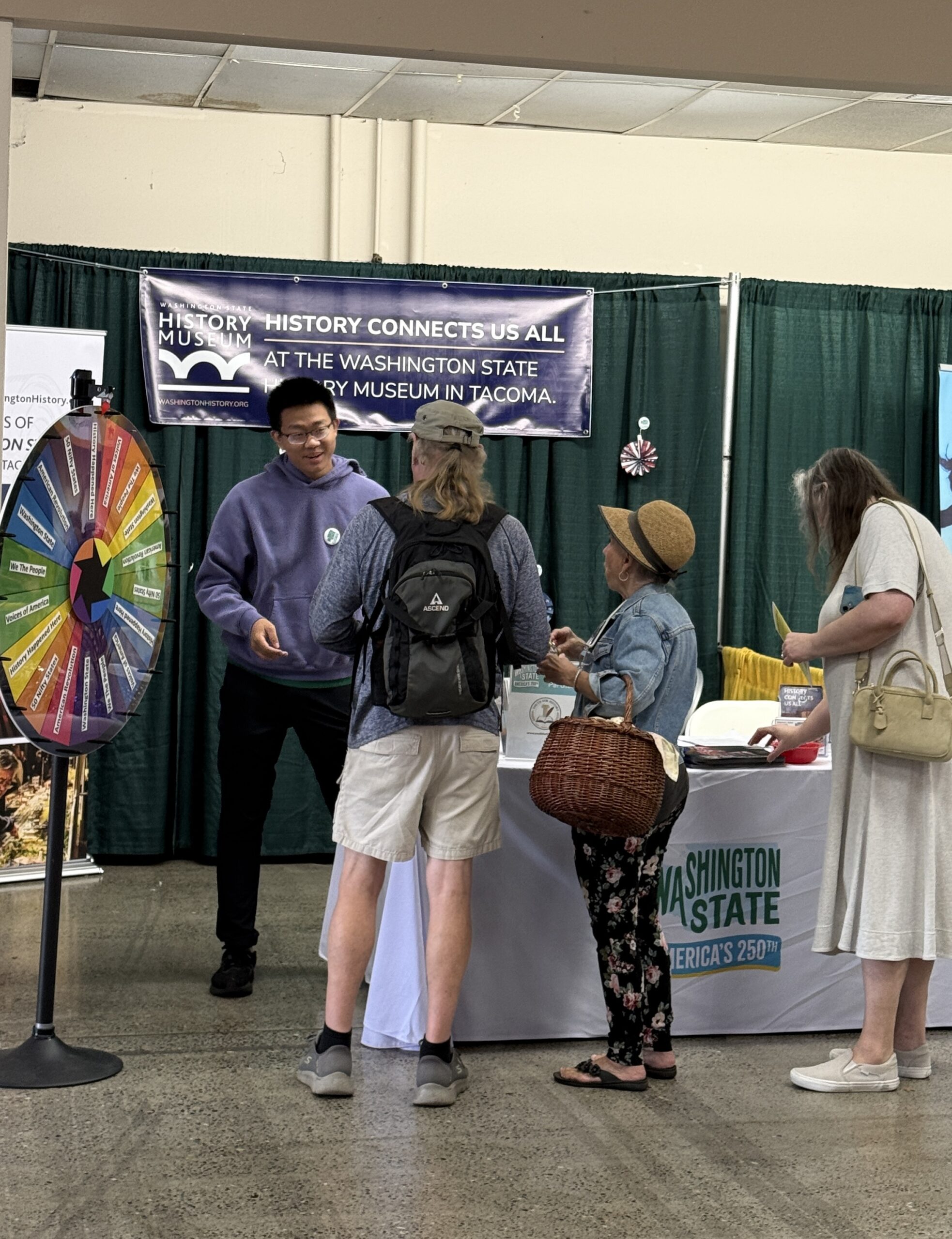 Visitors gather beside a volunteer and the colorful history activity wheel.